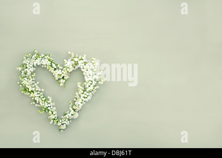 Fiore a forma di cuore ghirlanda di lilys della valle sul verde sullo sfondo di legno Foto Stock