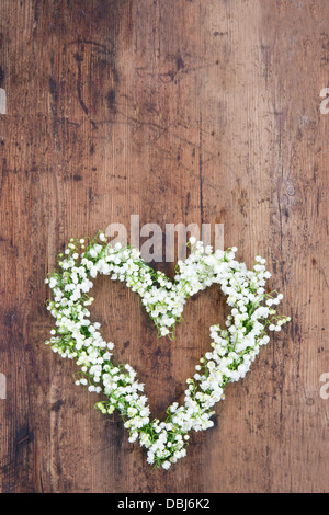 Fiore a forma di cuore ghirlanda di lilys della valle sul rustico sfondo di legno Foto Stock