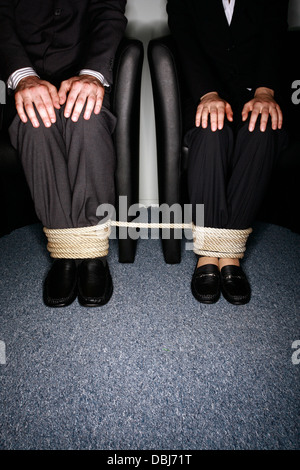 Maschio e femmina la gente di affari per le gambe legato Foto Stock