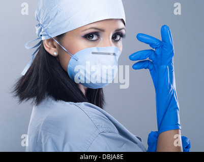 Femmina / infermiere Medico Chirurgo / indossando scrubs con guanti e maschera Foto Stock