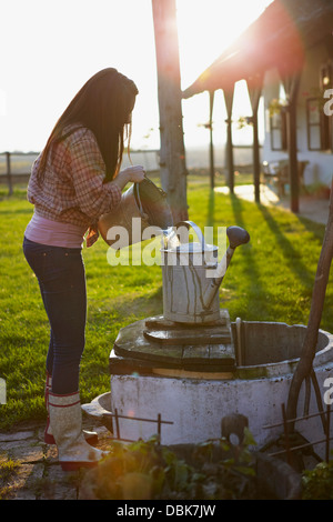 Giovane donna in Agriturismo versando acqua nella benna, Baranja, Croazia, Europa Foto Stock