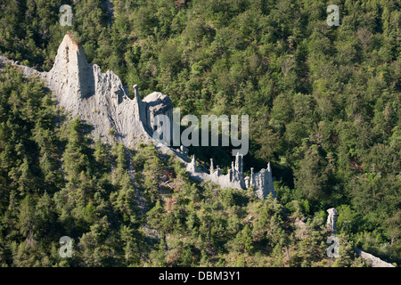 VISTA AEREA. Formazione geologica di hoodoos sulle pendici boscose sopra il lago Serre-Poncon. Le Sauze-du-Lac, Hautes-Alpes, Francia. Foto Stock