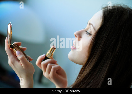 La donna a mettere su il rossetto, cercando in mano specchio, Copenhagen, Danimarca Foto Stock