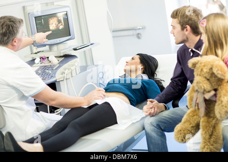 Donna incinta ricevendo ultrasuoni, mio marito e mia figlia a guardare, osijek, Croazia Foto Stock