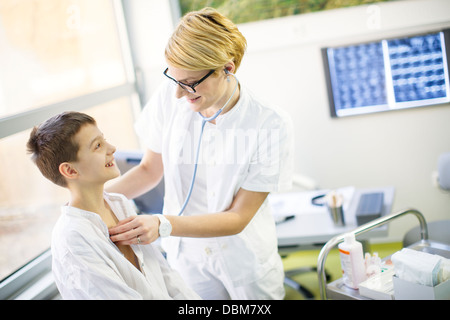 Medico donna utilizzando uno stetoscopio sul ragazzo sorridente, osijek, Croazia Foto Stock