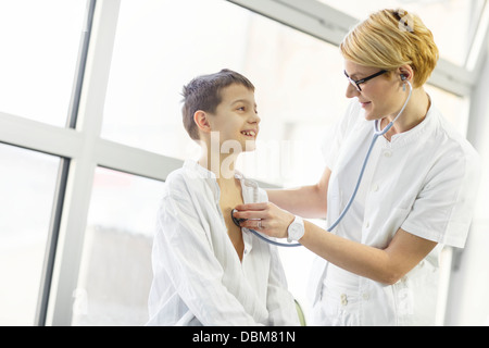 Medico donna utilizzando uno stetoscopio sul ragazzo sorridente, osijek, Croazia Foto Stock