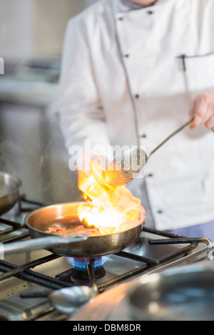 Lo Chef flambeing cibo in padella Foto Stock