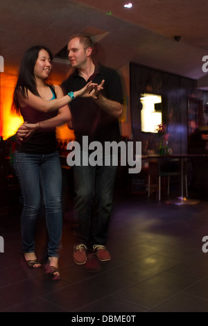 Coppia giovane ballare la salsa in un colorato bar Foto Stock