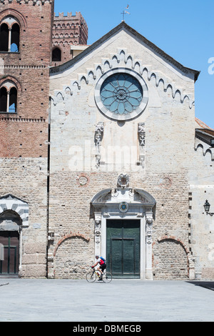 Ciclista in sella oltre la cattedrale di San Michele, Albenga, Italia settentrionale Foto Stock