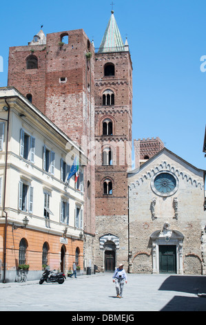 Uomo che cammina attraverso il San Michele piazza duomo entro la storica italiana del nord città di Albenga Foto Stock