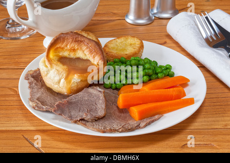 Roast Beef e Yorkshire pudding - con il sugo di carne, arrosto di patate, piselli e carote. Foto Stock