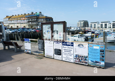 Cartelli e poster pubblicità la pesca e gite di piacere a West Bay Harbour Dorset Regno Unito Foto Stock