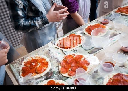 Vista dettagliata del cuoco di braccia e diverse pizze sul tavolo Foto Stock