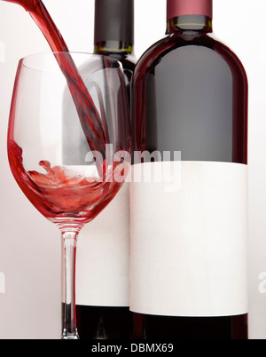 Bicchiere di vino rosso e due bottiglie di vino Foto Stock