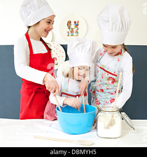 Tre bambine con chef hat preparazione impasto insieme, Monaco di Baviera, Germania Foto Stock