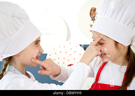 Due bambine con chef hat scherzando intorno, Monaco di Baviera, Germania Foto Stock