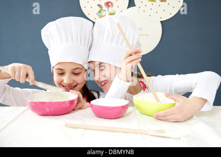 Bambine con chef hat preparare la pasta di pane, Monaco di Baviera, Germania Foto Stock