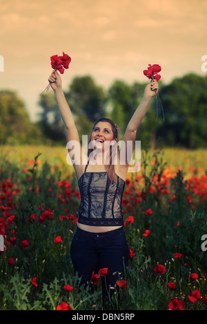 Giovane donna holding papaveri rossi in un campo di papavero, Croazia, Europa Foto Stock