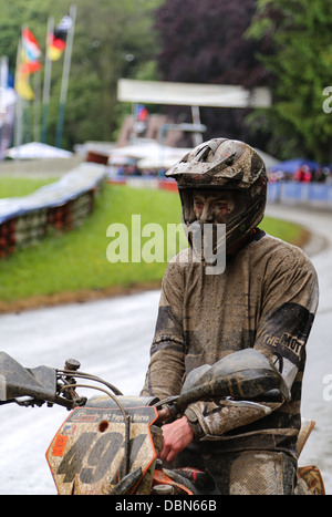 Supermoto rider pieno di fango riposo dopo la gara. focus sul pilota al primo piano. Foto Stock