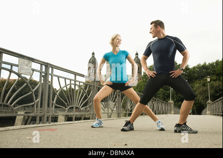 Coppia giovane stretching sul ponte, Monaco di Baviera, Germania Foto Stock