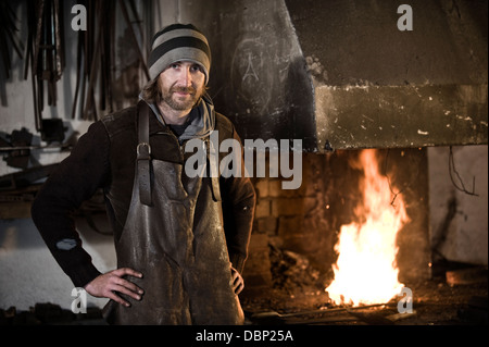 Fabbro in piedi in officina, fucina di background, Landshut, Baviera, Germania Foto Stock