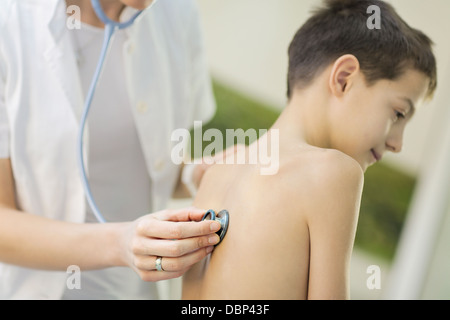 Medico donna utilizzando uno stetoscopio sul ragazzo sorridente, osijek, Croazia Foto Stock