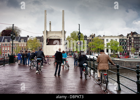 Le persone in attesa di sollevare il Ponte Magro (Olandese: Magere Brug) sul fiume Amstel di Amsterdam, Olanda, Paesi Bassi. Foto Stock