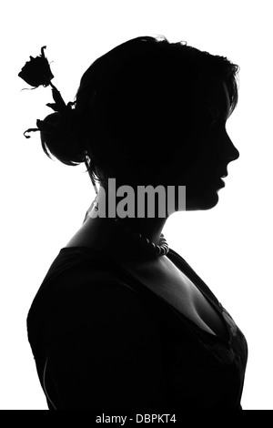 Una vista laterale, profilo, in bianco e nero la silhouette di un elegante, bella donna giovane con una rosa appassita in her hair bun Foto Stock