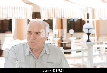 Nostalgica senior caucasica l uomo che guarda lontano di fronte a una casa in una giornata di sole Foto Stock