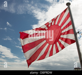 Il navale giapponese Ensign: il Rising Sun Bandiera, bianco con un disco rosso leggermente per il paranco con raggi 16 che si estendono. Foto Stock