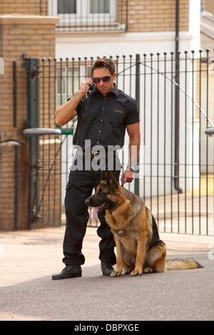 Una guardia di sicurezza con Pastore Tedesco cane da guardia parlare del walkie-talkie Foto Stock