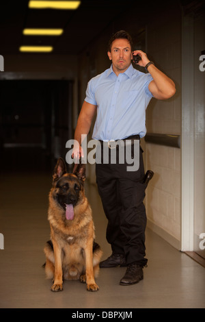 La guardia di sicurezza con Pastore Tedesco cane da guardia controllare i corridoi di un edificio di notte Foto Stock