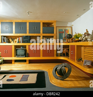 Abstract tappeto a motivi geometrici e pallido pavimenti in legno degli anni novanta in salotto con finestre da pavimento a soffitto montata l'unità di storage Foto Stock
