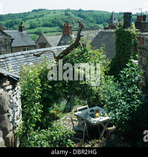 Piccolo tavolo in legno e sedie sul patio nel ripido pendio sopra il giardino sul tetto con una vista delle colline in lontananza Foto Stock