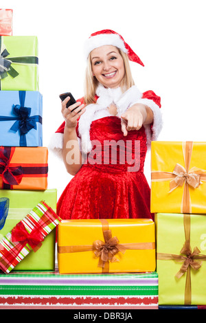 Felice donna in costume di Natale tenendo il telefono e rivolto a voi, isolati su sfondo bianco. Foto Stock
