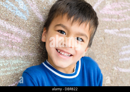 Felice ragazzo con il suo disegno sul marciapiede Foto Stock