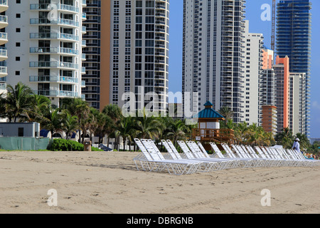 Skyline di condomini ultra-chic e fila di sedie a sdraio sulle spiagge sabbiose accolgono i vacanzieri per godersi un po' di tempo libero durante una giornata altrimenti impegnativa. Foto Stock