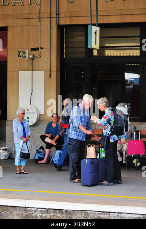Una coppia di anziani con i bagagli in attesa sulla piattaforma per un treno a Exeter St Davids stazione ferroviaria Foto Stock