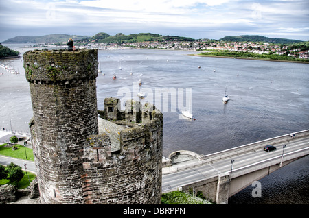 CONWY, Galles: Una vista del fiume Conwy e del paesaggio circostante, vista dalle torrette del castello di Conwy, una fortezza medievale del XIII secolo nel Galles del Nord. Il primo piano mostra alcuni dei bastioni e torrette ben conservati del castello, evidenziando l'impressionante architettura difensiva di questo sito patrimonio dell'umanità dell'UNESCO. Costruito da re Edoardo i durante la sua conquista del Galles, il castello di Conwy offre ai visitatori vedute panoramiche della città e dell'estuario sottostante. Foto Stock