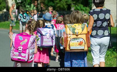 Futuro prima elementare di una scuola elementare a piedi accanto al loro maestro dopo la cerimonia di iscrizione in Boossen, un quartiere di Francoforte (Oder), Germania, 03 agosto 2013. I bambini di tornare a scuola dopo la pausa estiva nel Brandeburgo il 05 agosto 2013. Foto: Patrick Pleul Foto Stock