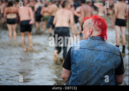 Un uomo che osserva la gente per divertirsi in una piscina di fango del Przystanek Woodstock music festival, Kostrzyn, Polonia. Foto Stock