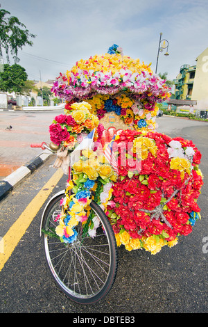 In Trishaw decorate con colorati fiori di seta parcheggiata su strada nella città portuale di Malacca Malaysia Foto Stock