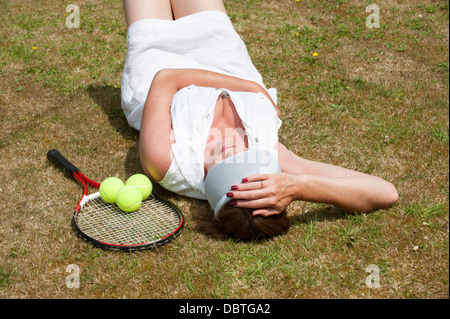 Ritratto di una femmina di giocatore di tennis la posa sull'erba Foto Stock