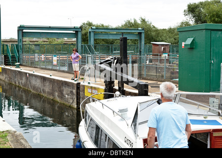 L'uomo navigazione in barca attraverso il blocco sul fiume Nene a Orton, Peterborough, Inghilterra Foto Stock