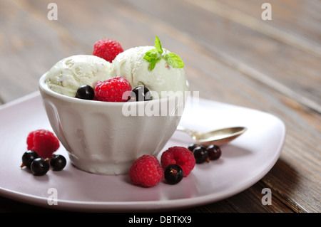 Gelato al lampone con la menta in vaso di ceramica con frutti di bosco freschi su sfondo di legno Foto Stock