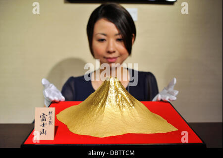 Agosto 2nd, 2013 : Tokyo, Giappone - un personale poste per una fotografia con il Monte Fuji realizzato da oro puro che è stato iniziato per essere visualizzate a Ginza branch di Ginza Tanaka, una gioielleria, in Ginza Chuo, Tokyo, Giappone, il 2 agosto 2013. Essa è stata realizzata per commemorare il Monte Fuji è la registrazione come sito del patrimonio mondiale, e che i clienti potrebbero acquistare la statua con il prezzo di circa JPY30 milioni. (Foto da Koichiro Suzuki/AFLO) Foto Stock