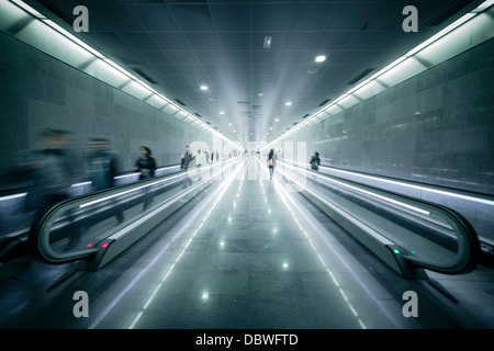 Gente che si muove su una superficie piana di scale mobili in una stazione ferroviaria Foto Stock