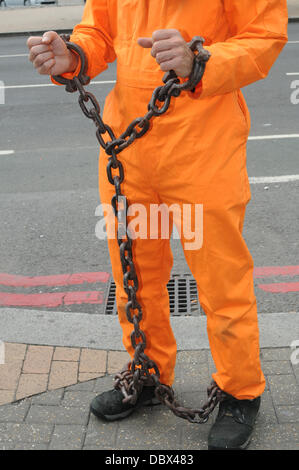 Londra, Regno Unito. 5 agosto 2013. Veglia di protesta per Shaker Aamer, ultimo cittadino del Regno Unito a Guantanamo, indossando tute arancioni una catena con le braccia e le gambe al di fuori a MI6 di Londra. Credito: Vedere Li/Alamy Live News Foto Stock