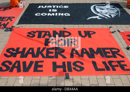 Londra, Regno Unito. 5 agosto 2013. Veglia di protesta per Shaker Aamer, ultimo cittadino del Regno Unito a Guantanamo, indossando tute arancioni una catena con le braccia e le gambe al di fuori a MI6 di Londra. Credito: Vedere Li/Alamy Live News Foto Stock