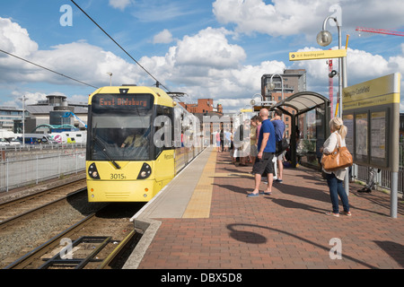 I passeggeri in attesa sulla piattaforma per tram Metrolink arrivando alla stazione Deansgate-Castlefield nel centro della città di Manchester Inghilterra England Regno Unito Foto Stock